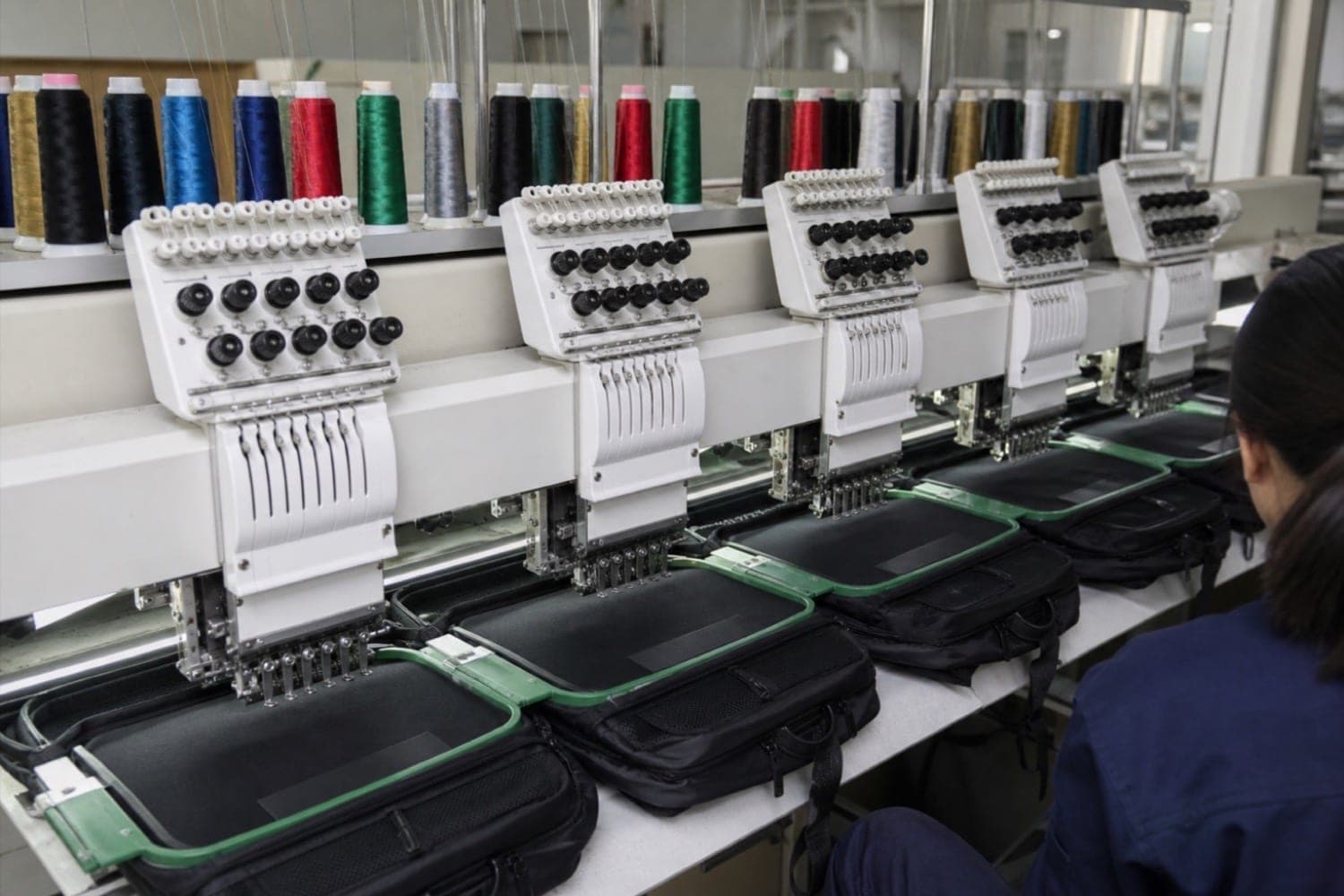 Multi-head embroidery machine applying artwork to a cut panel